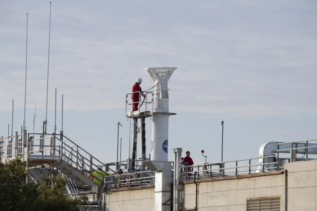 A man secures a cable to a rooftop pedestal.